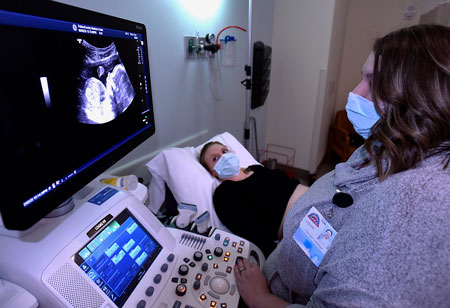 Picture of a female Ultrasound Tech showing a pregnant female an ultrasound of her baby.
