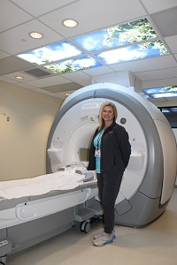 Female Nurse standing next to MRI scanner. MRI is accredited facility by the American College of Radiology.